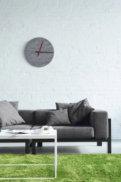 Intérieur confortable avec canapé gris moderne et horloge sur le mur — Photo de stock