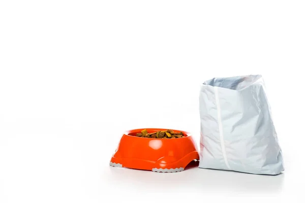 Close-up view of plastic bowl and bag with animal food isolated on white — Stock Photo