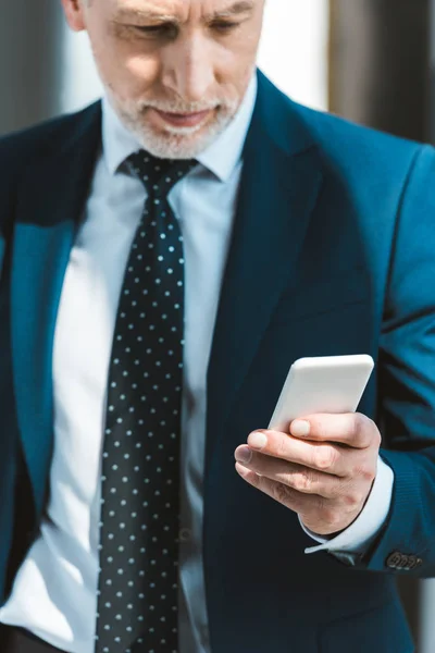 Plan recadré d'un homme d'affaires senior sérieux utilisant un smartphone — Photo de stock