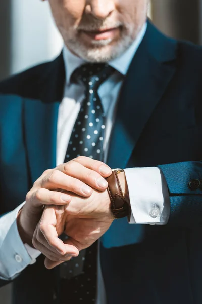 Обрезанный снимок старшего бизнесмена в формальной одежде проверяющего наручные часы — стоковое фото