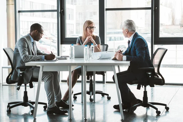 Professionelle multiethnische Geschäftsleute arbeiten gemeinsam am Tisch in modernen Büros — Stockfoto