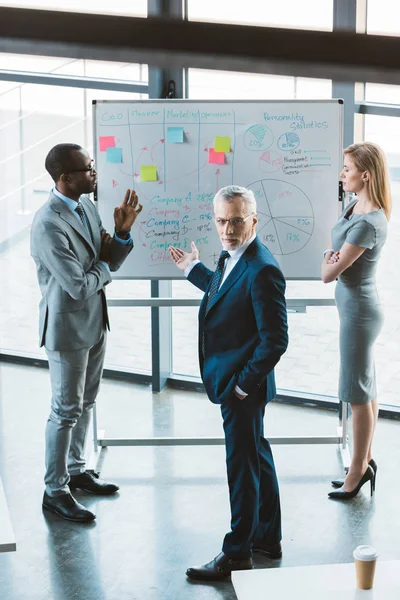 High angle view of professional multiethnic business people discussing charts and graphs on whiteboard — Stock Photo