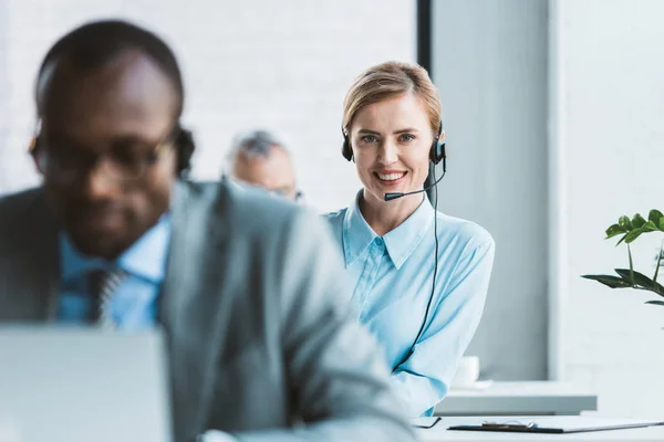 Foyer sélectif de femme d'affaires attrayante dans le casque souriant à la caméra — Photo de stock