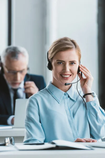 Beautiful businesswoman using headset and smiling at camera — Stock Photo