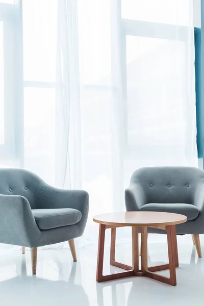 Table ronde en bois et fauteuils vides confortables dans la salle blanche — Photo de stock