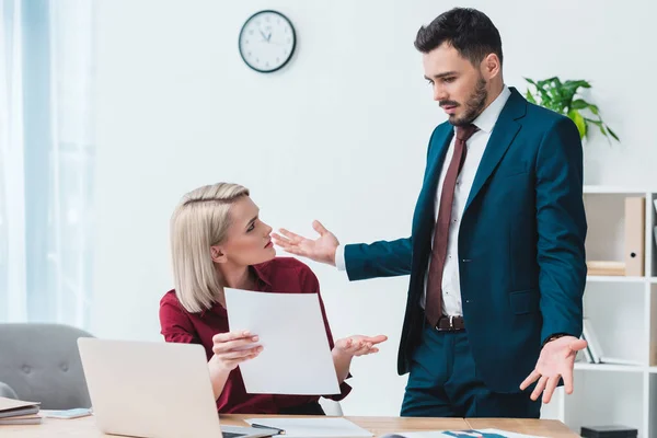 Young business people looking at each other and arguing at workplace — Stock Photo