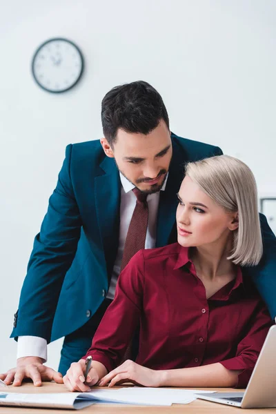 Attractive young businessman and businesswoman flirting at workplace — Stock Photo