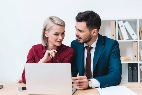 Beaux jeunes gens d'affaires utilisant un ordinateur portable tout en travaillant ensemble dans le bureau — Photo de stock