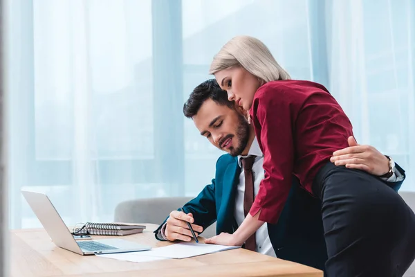 Seductive young couple embracing while working together in office — Stock Photo