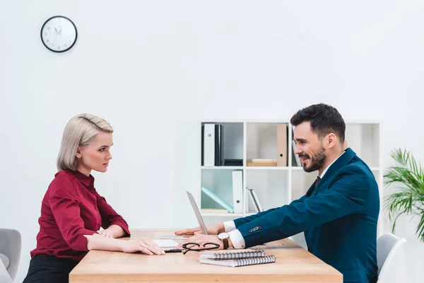 Vista lateral de los jóvenes empresarios mirándose mientras están sentados en la oficina - foto de stock