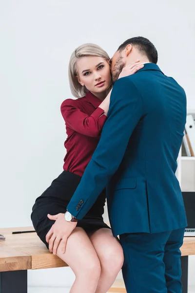 Sexy young couple of business people kissing and flirting at workplace — Stock Photo