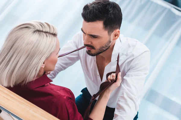 Sexy joven pareja mirando el uno al otro en los juegos previos en el lugar de trabajo - foto de stock