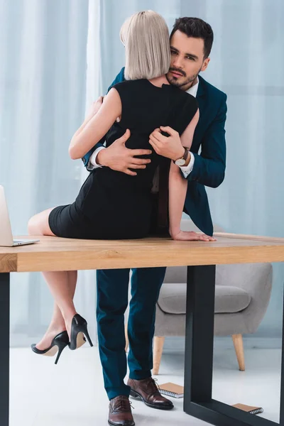 Businessman and businesswoman hugging in foreplay at workplace — Stock Photo