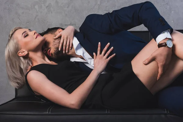 Sexy jeune couple câlins et baisers dans les préliminaires sur canapé — Photo de stock