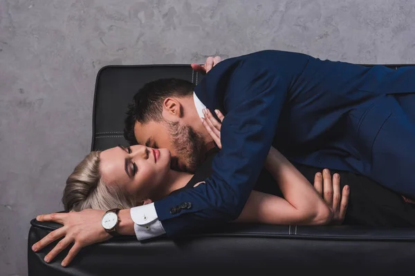 Side view of sexy young couple kissing on couch — Stock Photo