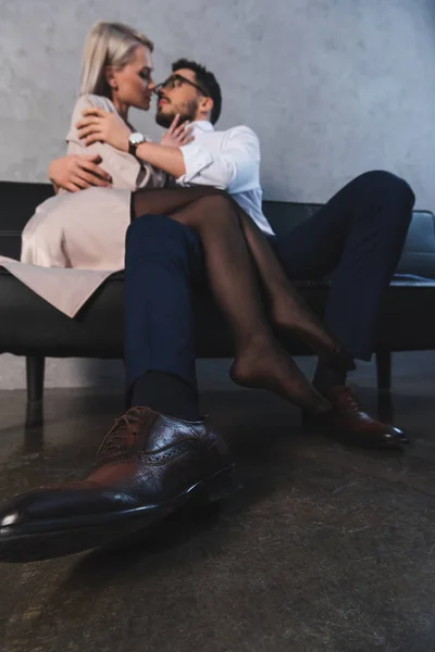 Low angle view of sexy young couple hugging and kissing on couch — Stock Photo