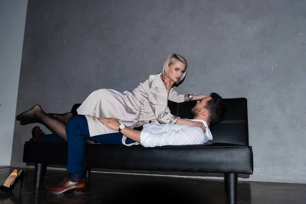 Bella giovane coppia sdraiata sul divano in preliminari, ragazza guardando la fotocamera — Foto stock