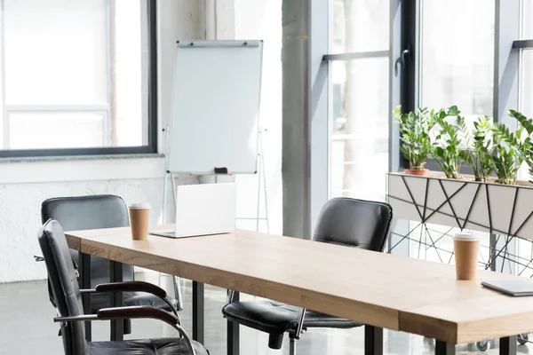 Einweg-Kaffeetassen und Laptop auf Holztisch im modernen Büro — Stockfoto