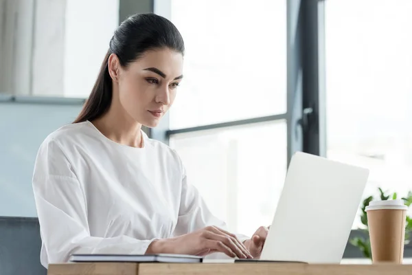 Schöne junge Geschäftsfrau arbeitet mit Laptop im Büro — Stockfoto