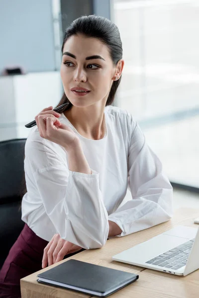 Hermosa sonriente joven empresaria mirando hacia otro lado en la oficina - foto de stock