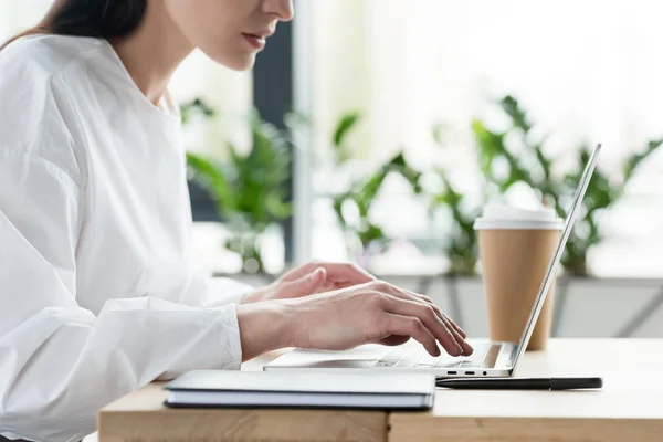 Tiro cortado de jovem empresária usando laptop no local de trabalho — Stock Photo