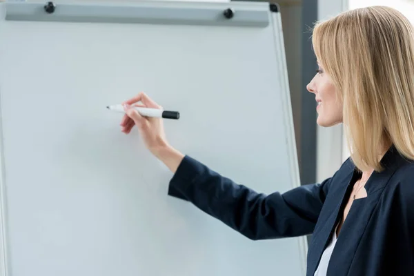 Souriant professionnel femme d'affaires écrit sur tableau blanc vierge — Photo de stock