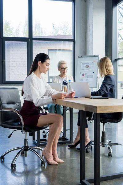Три профессиональные деловые женщины в формальной одежде работают за столом в офисе — стоковое фото