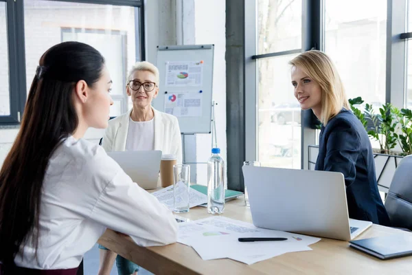 Lächelnde schöne Geschäftsfrauen im Gespräch bei einem Treffen im Büro — Stockfoto