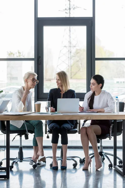Attractive businesswomen using laptop at meeting in office — Stock Photo
