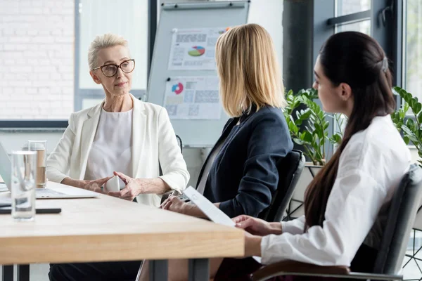 Side view of beautiful businesswomen talking at meeting in office — Stock Photo