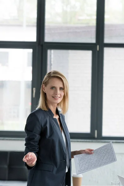 Séduisante femme d'affaires détenant des documents et des gestes en fonction — Photo de stock