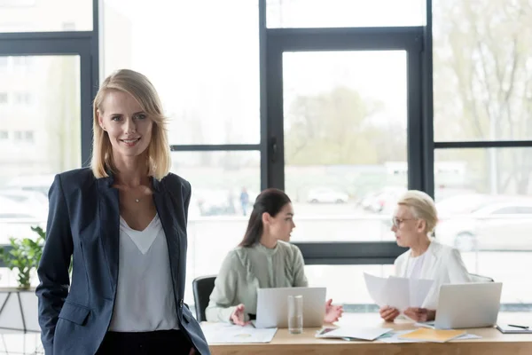 Attractive businesswoman standing in office and looking at camera — Stock Photo