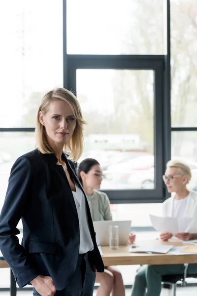 Beautiful businesswoman standing in office and looking at camera — Stock Photo