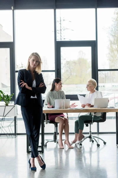 Beautiful businesswoman standing with crossed arms at meeting in office — Stock Photo