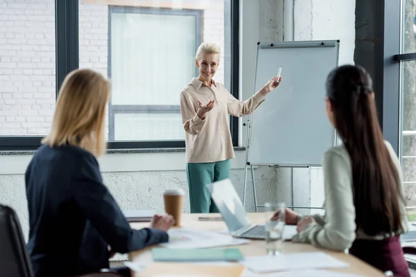 Lächelnde Seniorin stellt Projekt Kollegen bei Besprechung im Büro vor — Stockfoto