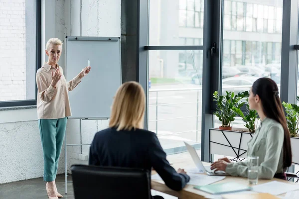 Femme d'affaires senior présentant le projet à ses collègues lors d'une réunion au bureau — Photo de stock