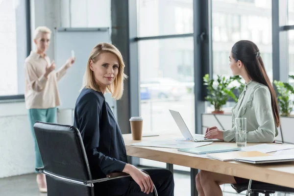 Schöne blonde Geschäftsfrau blickt während eines Treffens im Büro in die Kamera — Stockfoto