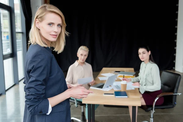 Belle femme d'affaires et ses collègues à la réunion au bureau — Photo de stock