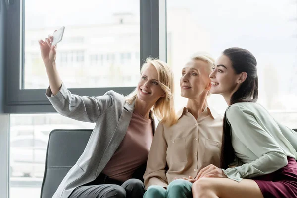 Красиві бізнес-леді беруть селфі зі смартфоном в офісі — стокове фото