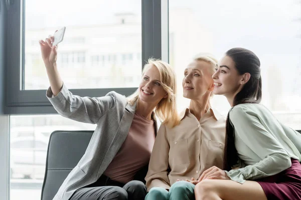 Hermosas empresarias tomando selfie con teléfono inteligente en la oficina - foto de stock
