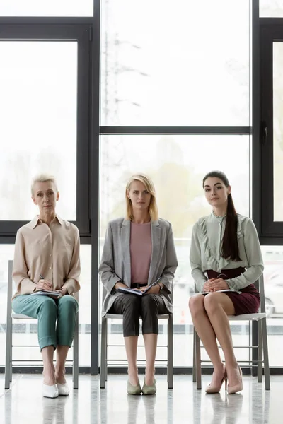 Mulheres de negócios bonitas sentadas em cadeiras durante a reunião no escritório — Fotografia de Stock