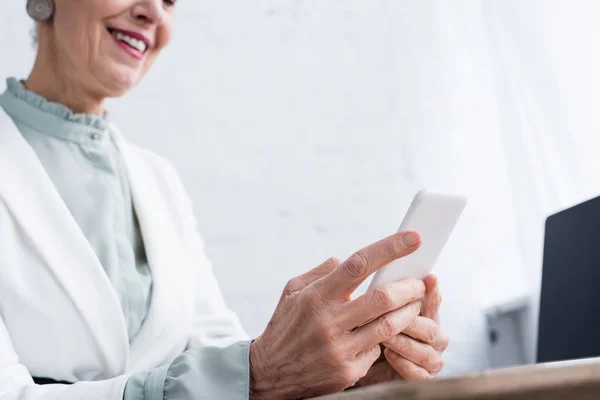 Cropped view of smiling senior businesswoman using smartphone — Stock Photo