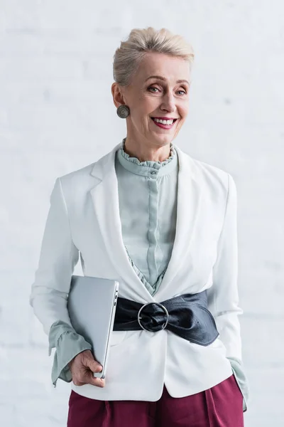 Smiling senior businesswoman with laptop in office — Stock Photo