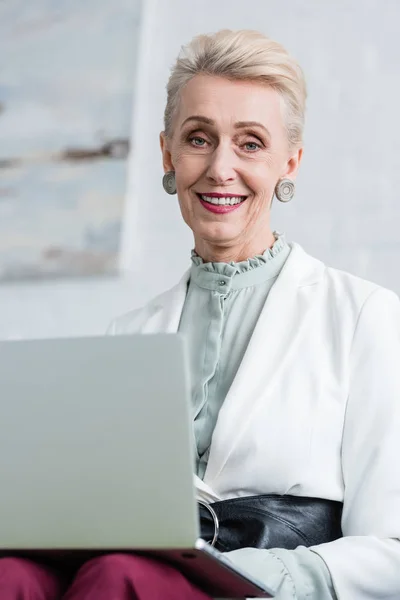 Elegante donna d'affari anziana sorridente usando il computer portatile — Foto stock