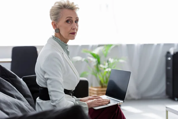 Executive senior businesswoman using laptop in office — Stock Photo