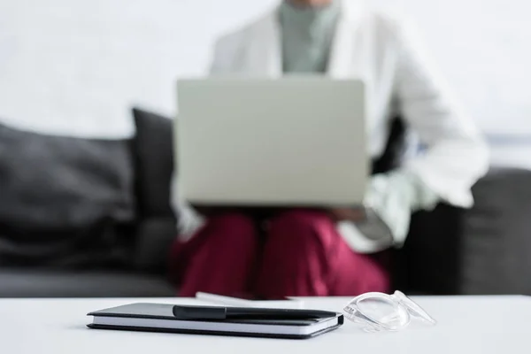 Selective focus of businesswoman using laptop, diary, pen and glasses lying on table on foreground — Stock Photo