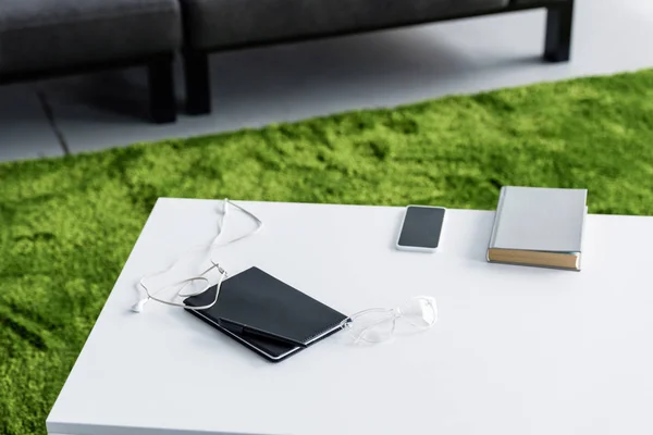 Libro, smartphone y tableta digital con auriculares en mesa blanca - foto de stock