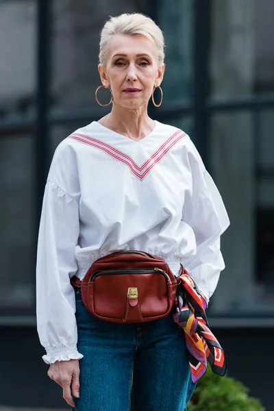 Fashionable senior woman in trendy outfit posing with belt bag — Stock Photo