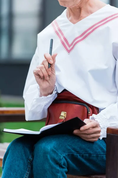 Vista recortada de la mujer en traje de moda escritura en el diario — Stock Photo