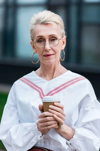 Attraente elegante donna anziana in occhiali alla moda che tengono il caffè per andare — Foto stock